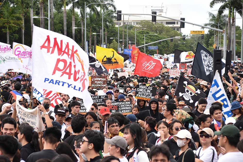 Protesters holding banners and flags at a large street demonstration demanding anti-corruption action