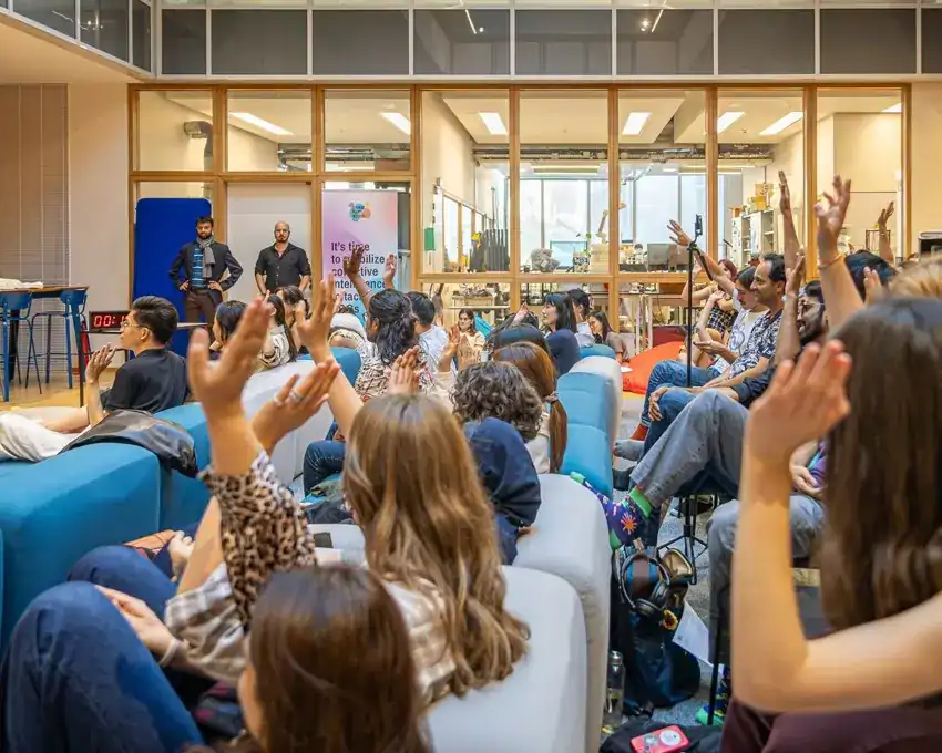 Audience members raising hands during interactive session in bright modern learning space