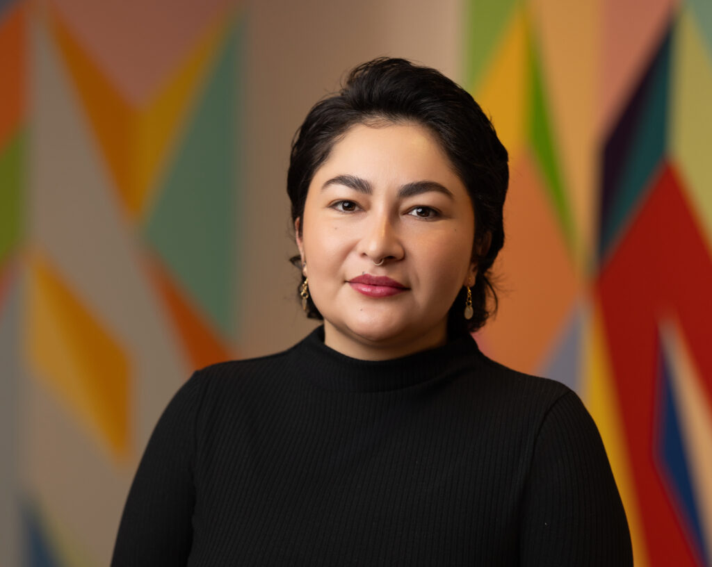 KD Chavez, executive director of Climate Justice Alliance, in black turtleneck against colorful abstract background